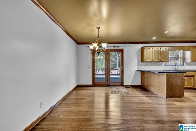 kitchen with crown molding, a chandelier, light hardwood / wood-style flooring, pendant lighting, and backsplash