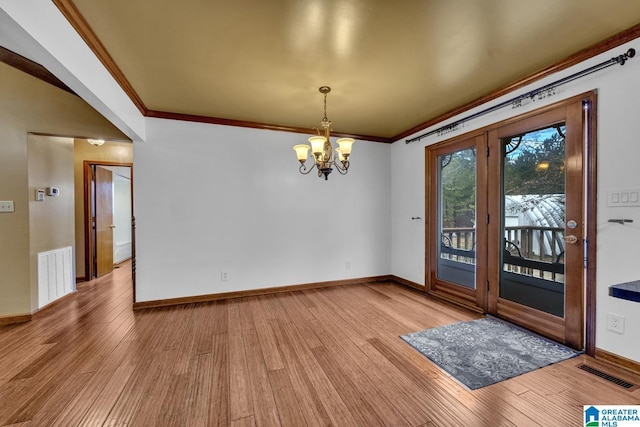 unfurnished dining area featuring ornamental molding, wood-type flooring, and a notable chandelier