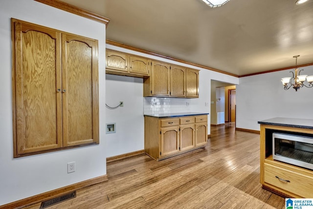 kitchen featuring crown molding, backsplash, decorative light fixtures, and light wood-type flooring