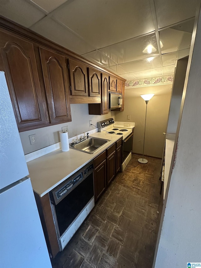 kitchen with white appliances, dark parquet flooring, sink, and dark brown cabinets