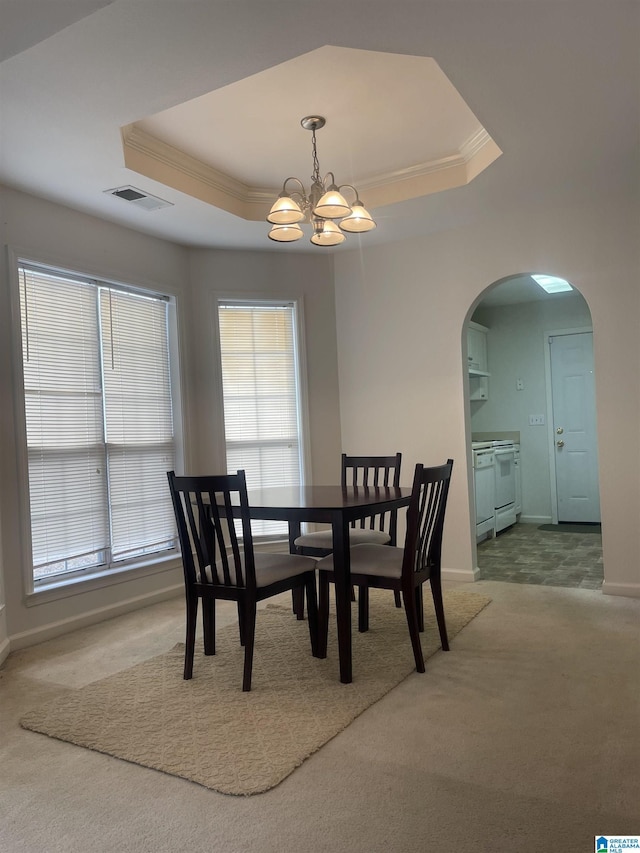 carpeted dining space featuring a chandelier, ornamental molding, and a raised ceiling