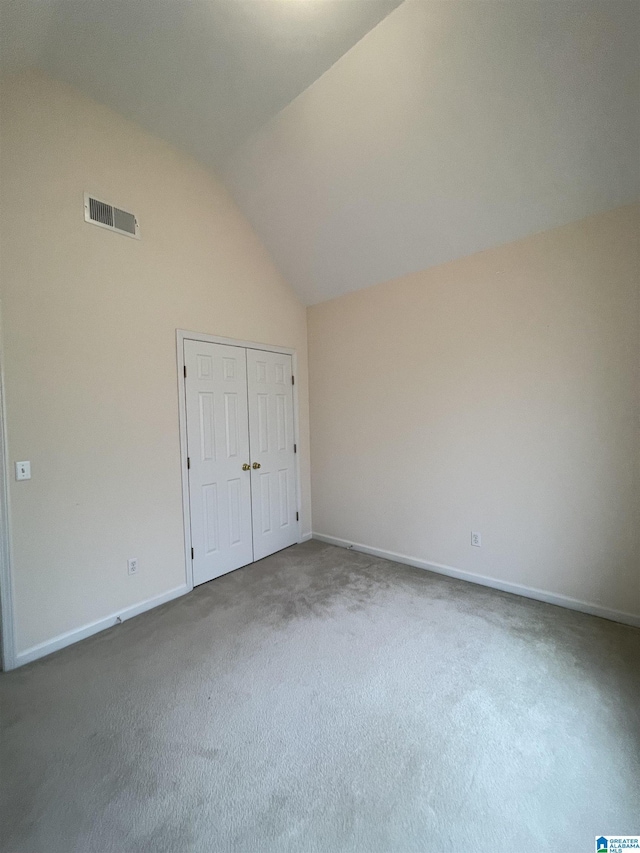 unfurnished bedroom featuring high vaulted ceiling, a closet, and dark colored carpet