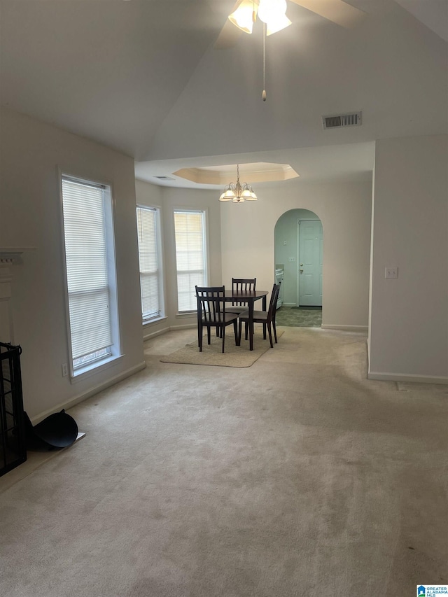 dining area featuring an inviting chandelier, a tray ceiling, and light carpet