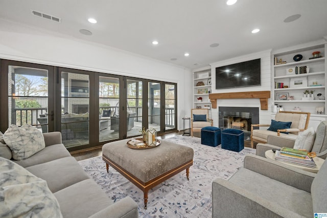 living room with hardwood / wood-style flooring, plenty of natural light, ornamental molding, and a large fireplace