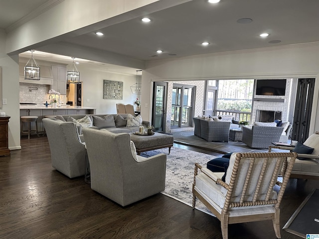 living room featuring dark wood-type flooring, a fireplace, and ornamental molding