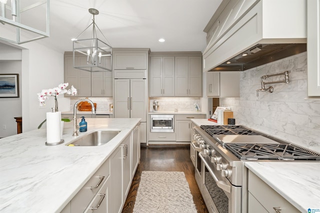 kitchen with premium range hood, sink, hanging light fixtures, built in appliances, and light stone countertops