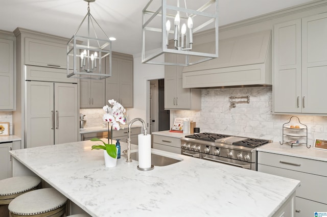 kitchen featuring sink, custom exhaust hood, premium appliances, gray cabinets, and an island with sink