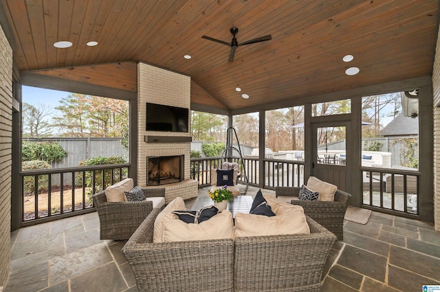 sunroom / solarium featuring wood ceiling, ceiling fan, lofted ceiling, and an outdoor brick fireplace