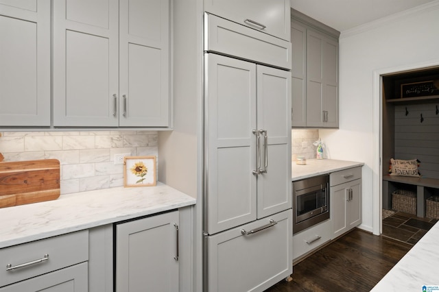 kitchen featuring gray cabinets, light stone countertops, built in appliances, and decorative backsplash