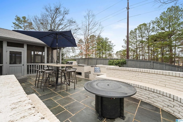 view of patio with an outdoor kitchen, a grill, an outdoor fire pit, and a sunroom