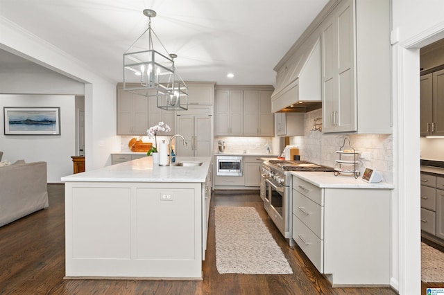 kitchen featuring sink, a kitchen island with sink, hanging light fixtures, stainless steel appliances, and decorative backsplash