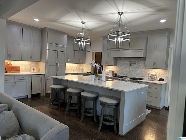 kitchen featuring a center island with sink, gray cabinetry, and decorative light fixtures