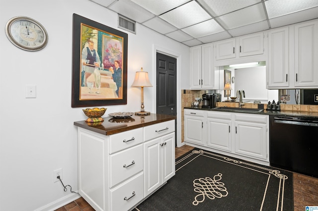 kitchen featuring a paneled ceiling, tasteful backsplash, black dishwasher, sink, and white cabinets