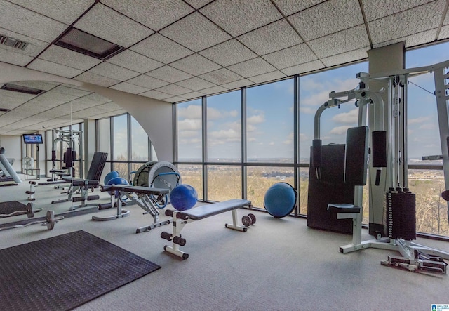 gym with a drop ceiling and a wall of windows