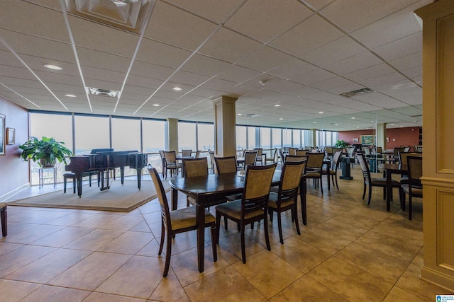 tiled dining area featuring ornate columns, floor to ceiling windows, and a drop ceiling