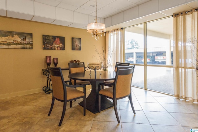 dining area featuring a drop ceiling, light tile patterned floors, and a notable chandelier