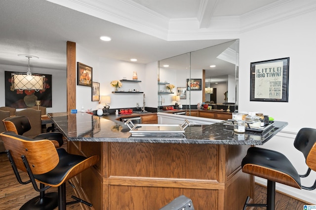 kitchen with hanging light fixtures, hardwood / wood-style floors, ornamental molding, and kitchen peninsula