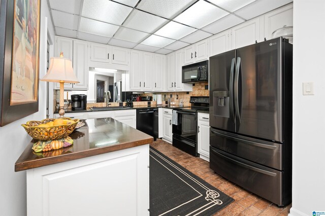 kitchen featuring white cabinetry, sink, a drop ceiling, and black appliances