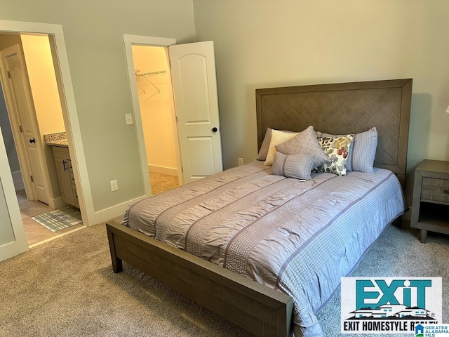 bedroom with a spacious closet, light colored carpet, ensuite bath, and a closet