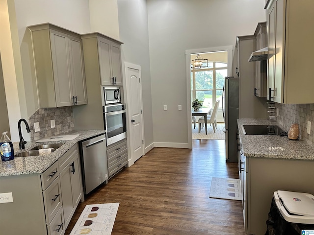 kitchen with appliances with stainless steel finishes, light stone countertops, sink, and gray cabinetry