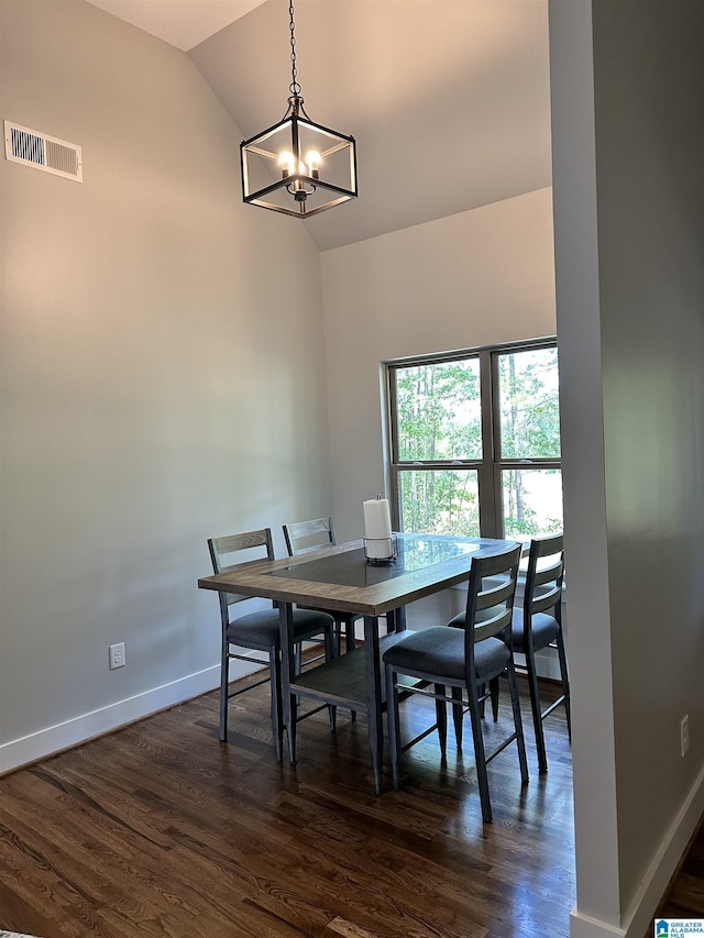 dining area featuring dark wood-type flooring, high vaulted ceiling, and an inviting chandelier