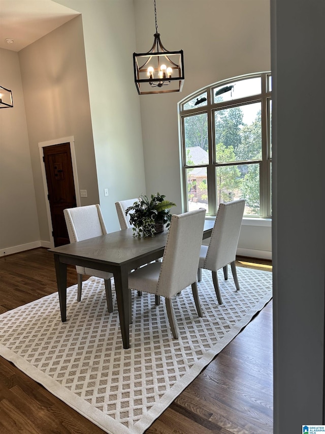 dining room featuring a high ceiling, dark wood-type flooring, and an inviting chandelier