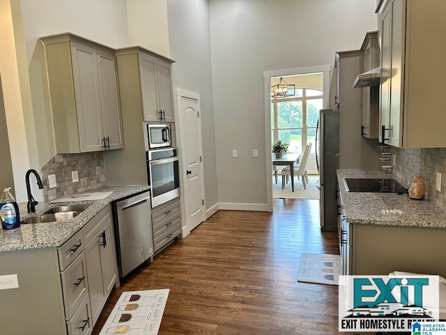 kitchen with sink, gray cabinetry, light stone counters, dark hardwood / wood-style floors, and stainless steel appliances