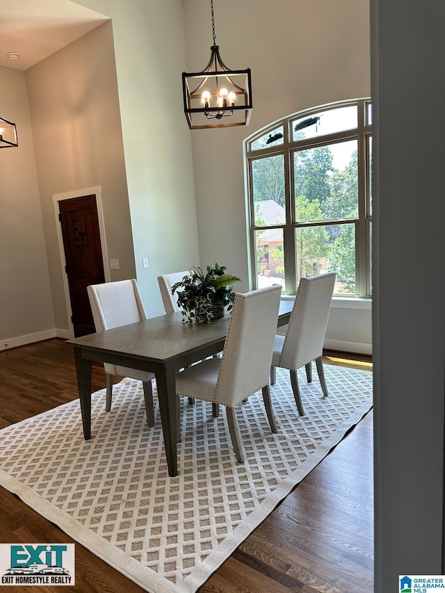 dining area featuring a towering ceiling, dark hardwood / wood-style floors, and a notable chandelier