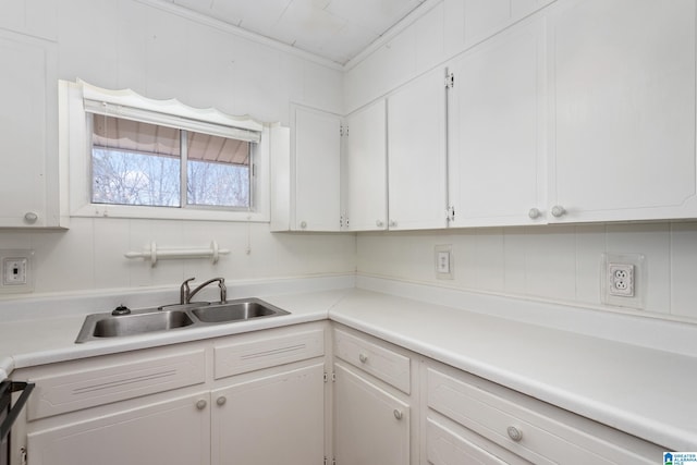 kitchen featuring ornamental molding, sink, and white cabinets