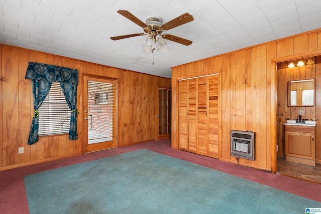 unfurnished living room with carpet, sink, heating unit, and ceiling fan