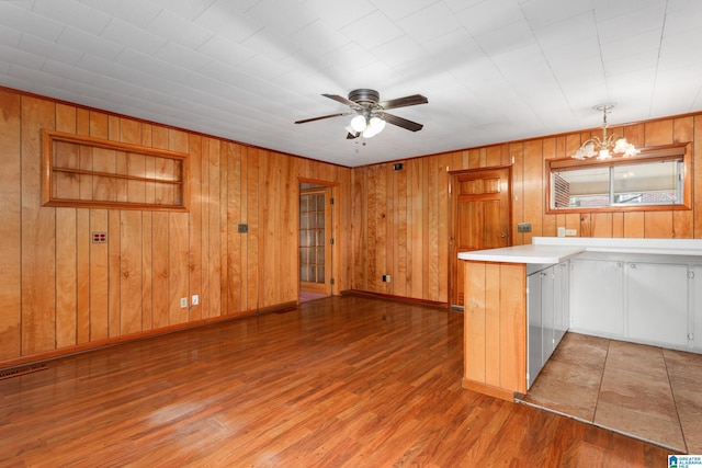 kitchen featuring pendant lighting, wood-type flooring, ceiling fan with notable chandelier, and white cabinets