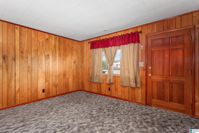 carpeted spare room with wooden walls