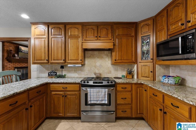 kitchen featuring light stone counters, light tile patterned floors, tasteful backsplash, and stainless steel appliances