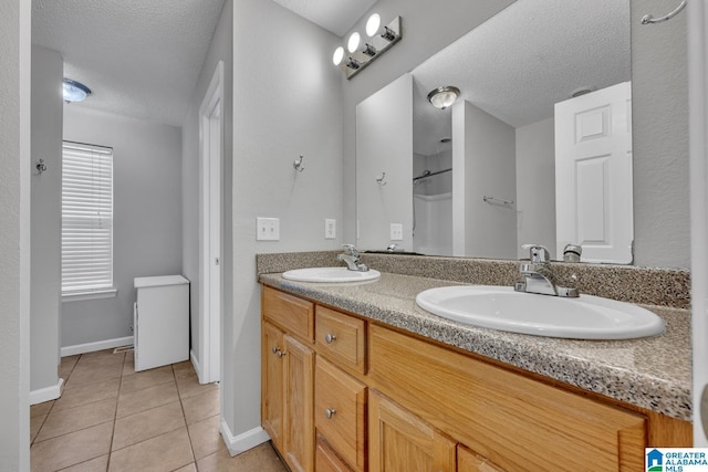 bathroom with tile patterned flooring, vanity, and a textured ceiling