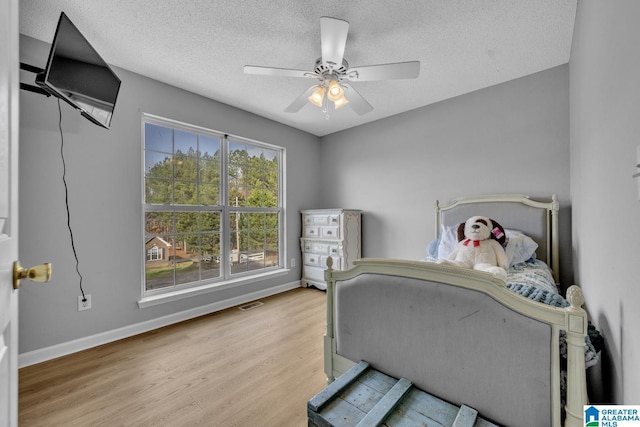 bedroom with ceiling fan, a textured ceiling, and light hardwood / wood-style floors