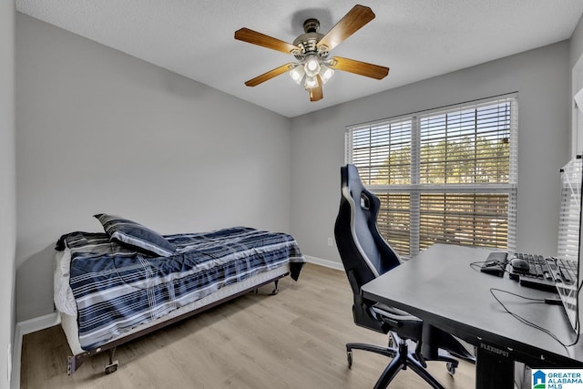 bedroom with ceiling fan, a textured ceiling, and light hardwood / wood-style floors