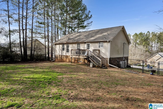 rear view of house featuring a wooden deck, central AC unit, and a lawn