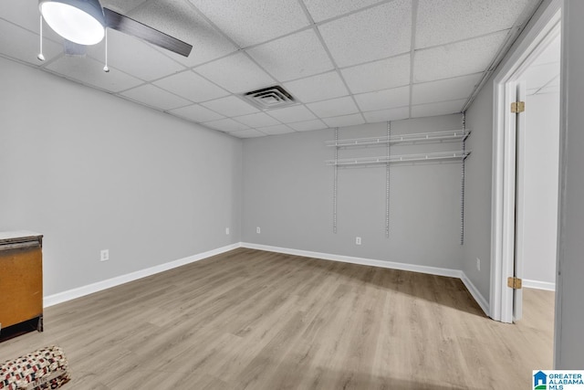 basement with a paneled ceiling, ceiling fan, and light wood-type flooring