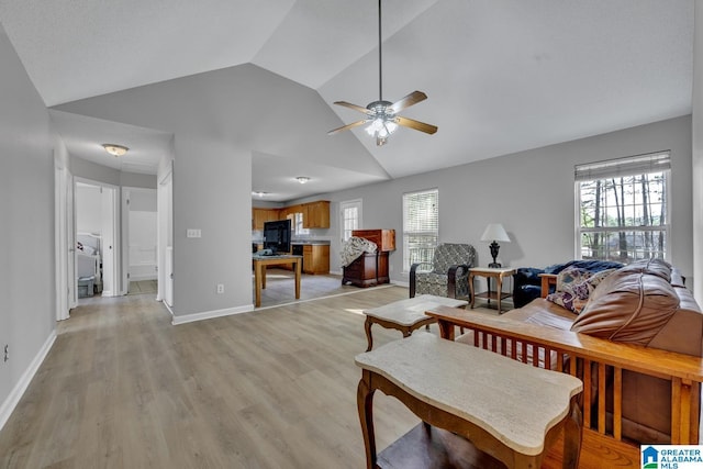 living room with ceiling fan, lofted ceiling, plenty of natural light, and light wood-type flooring