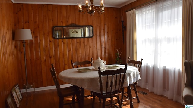 dining area with hardwood / wood-style flooring, a chandelier, and wood walls