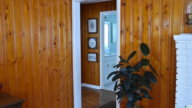 hall with dark hardwood / wood-style flooring, sink, and wood walls