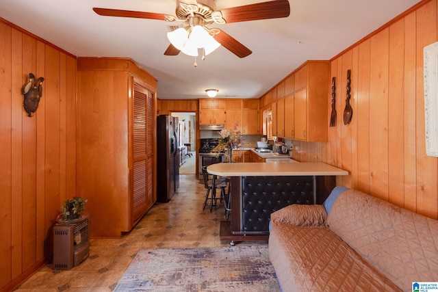 kitchen with stainless steel appliances, a breakfast bar area, wood walls, and kitchen peninsula