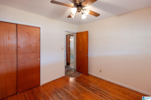 unfurnished bedroom featuring hardwood / wood-style flooring, ceiling fan, and a closet