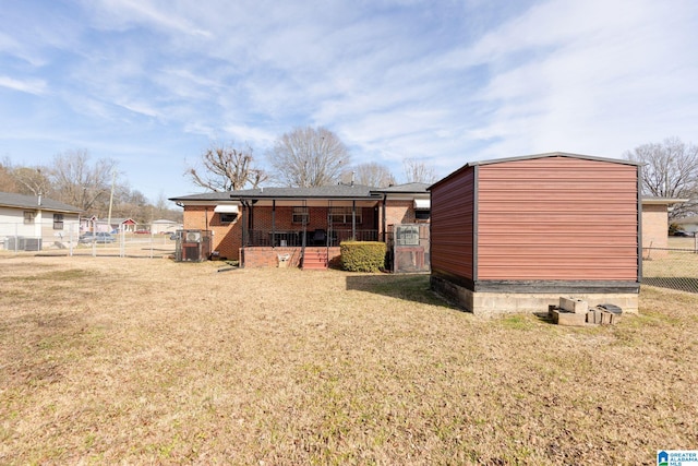 rear view of house featuring an outdoor structure and a lawn