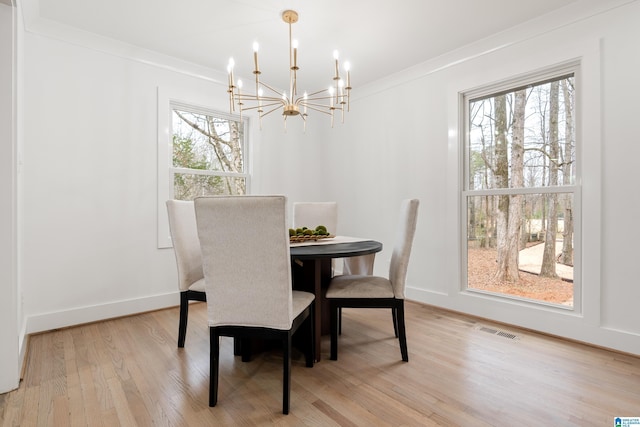 dining space featuring crown molding, a wealth of natural light, a chandelier, and light wood-type flooring