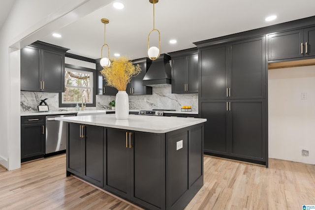 kitchen with dishwasher, hanging light fixtures, a center island, light hardwood / wood-style floors, and custom range hood