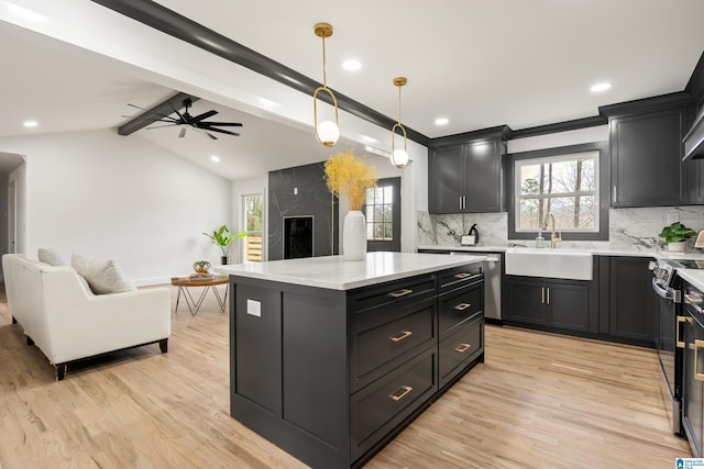 kitchen with sink, a center island, light hardwood / wood-style flooring, hanging light fixtures, and stove