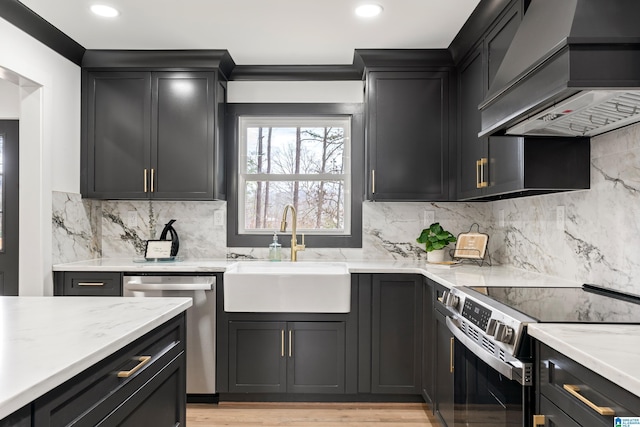 kitchen with sink, appliances with stainless steel finishes, premium range hood, tasteful backsplash, and light stone counters