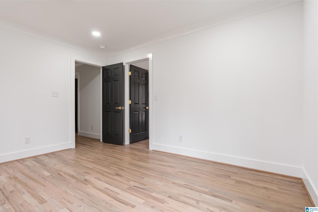 spare room featuring crown molding and light wood-type flooring