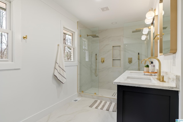 bathroom featuring vanity, a shower with shower door, and a healthy amount of sunlight